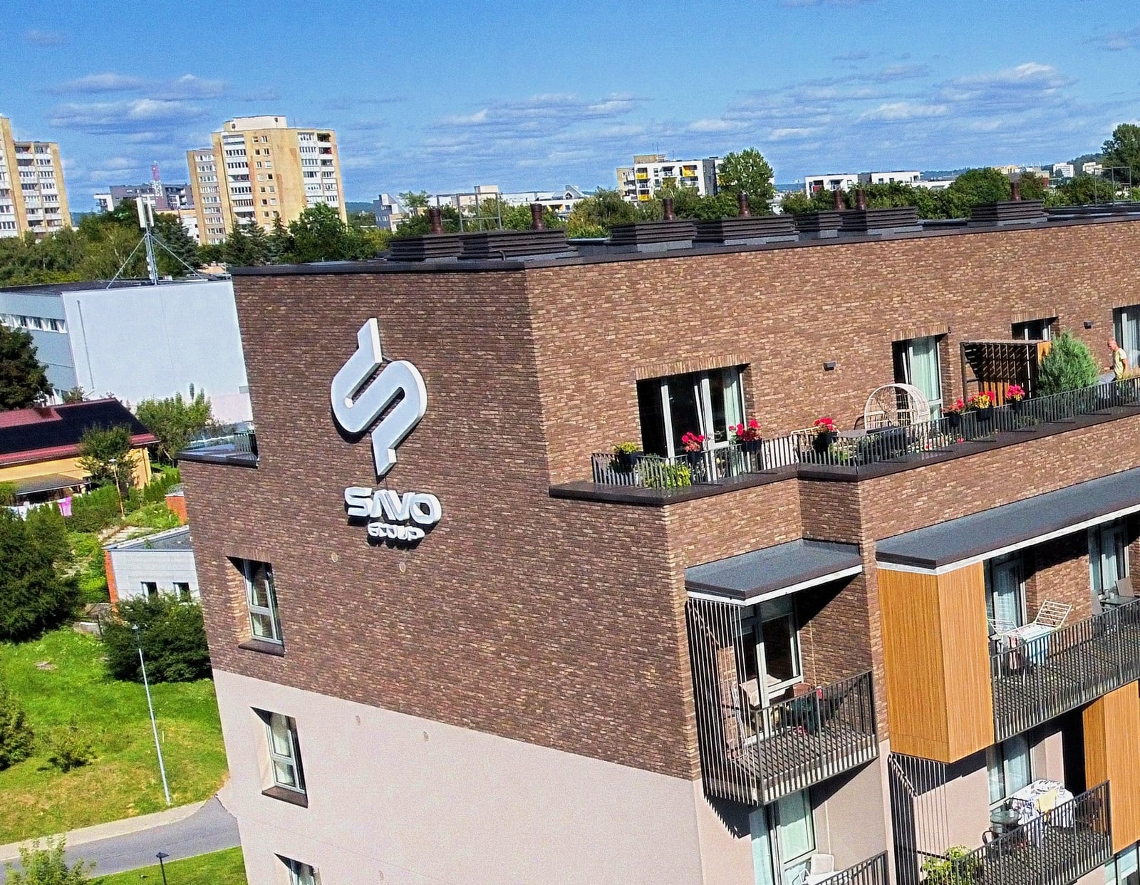 The SAVO monogram and wordmark painted large on the brick end wall of a residential building in Vilnius