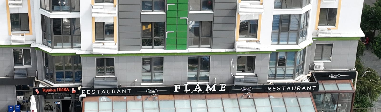 The FLAME restaurant sign running along the ground floor of a SAVO building, above its terrace