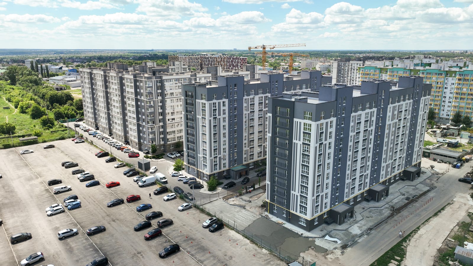 A newly finished grey and white block in Evromisto by SAVO, with the site still open in front of it and a tower crane behind