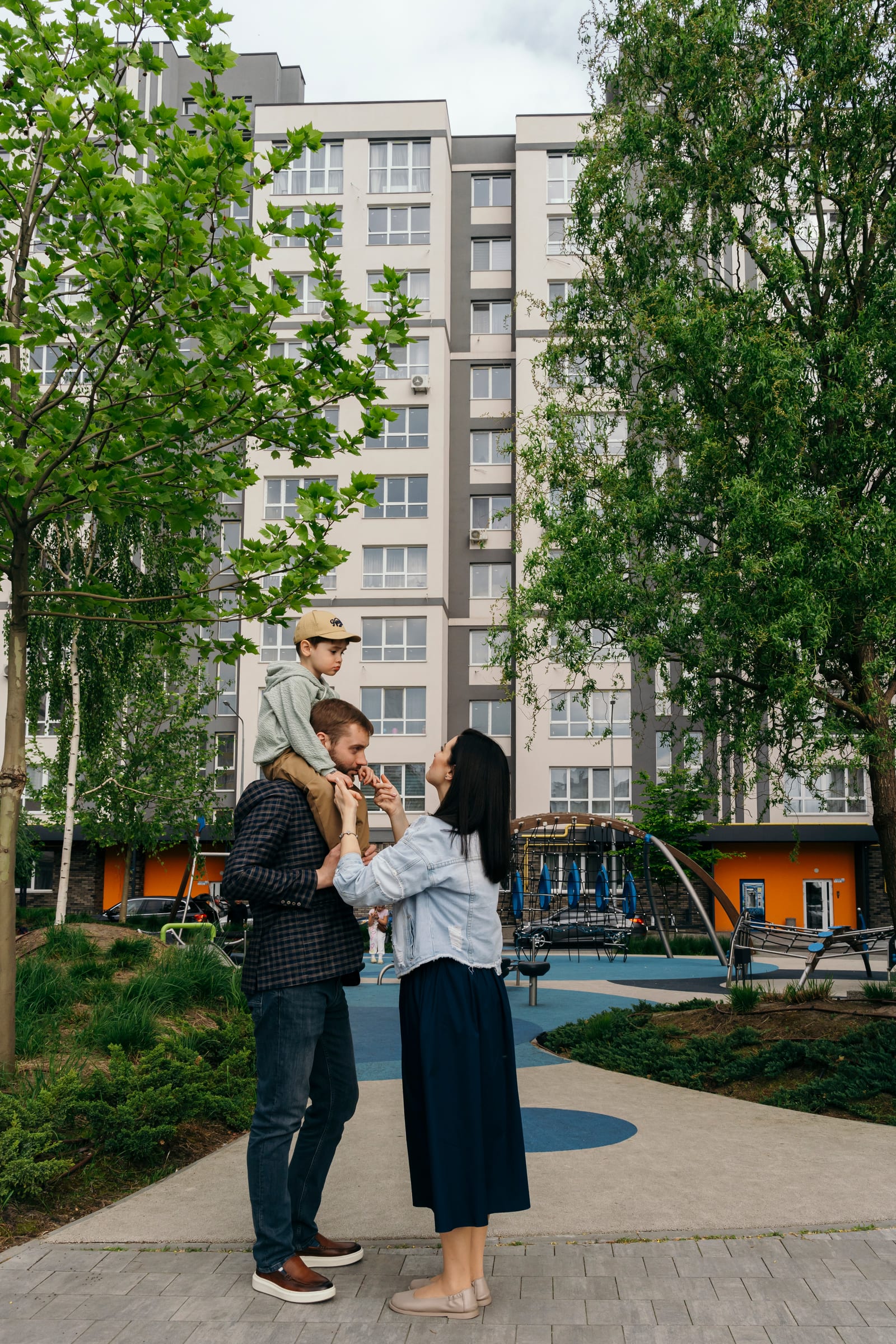 A father with his son on his shoulders and the mother beside him, standing in the courtyard of a SAVO district.