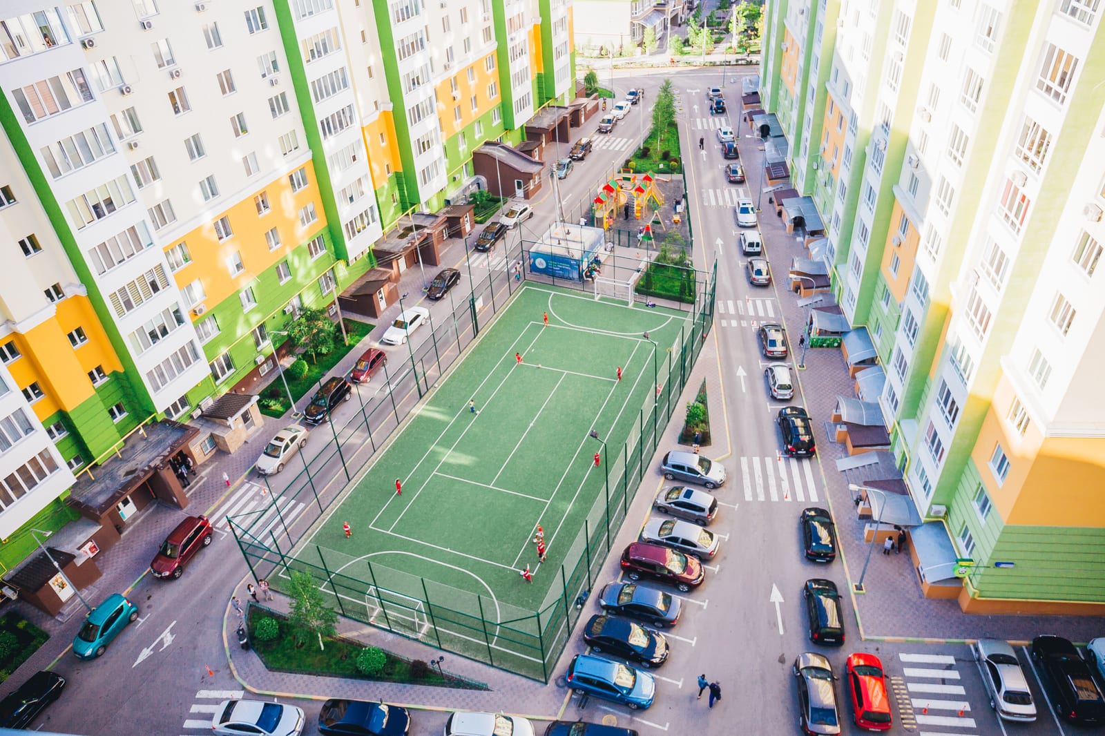 A green five-a-side pitch enclosed by high nets inside one of the courtyards, with the buildings standing behind it.