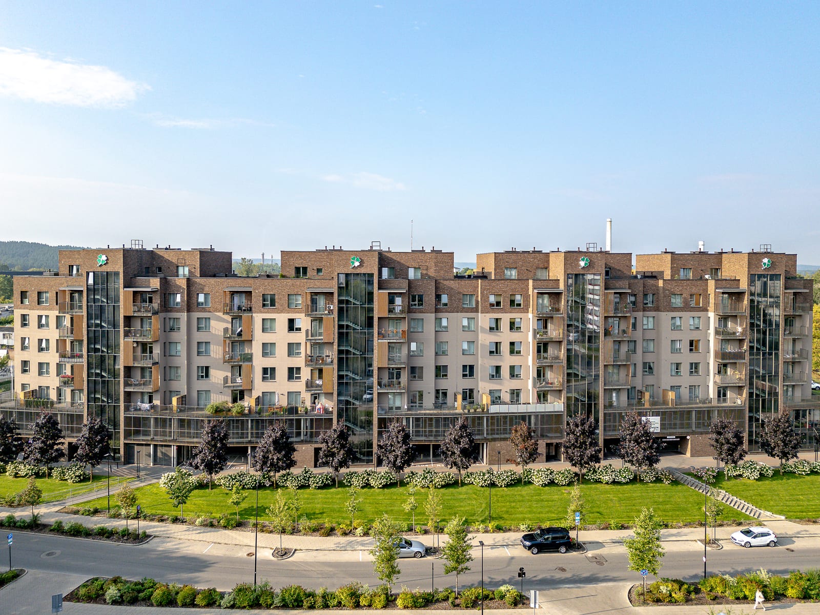 Lucky Homes by SAVO in Vilnius seen from the air: the full row of clinker-brick blocks with glazed stair towers, lawns and flowering hydrangeas along the street